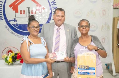 Minister of Housing and Water Collin Croal handing over a housing voucher to a resident of Laing Avenue in Georgetown