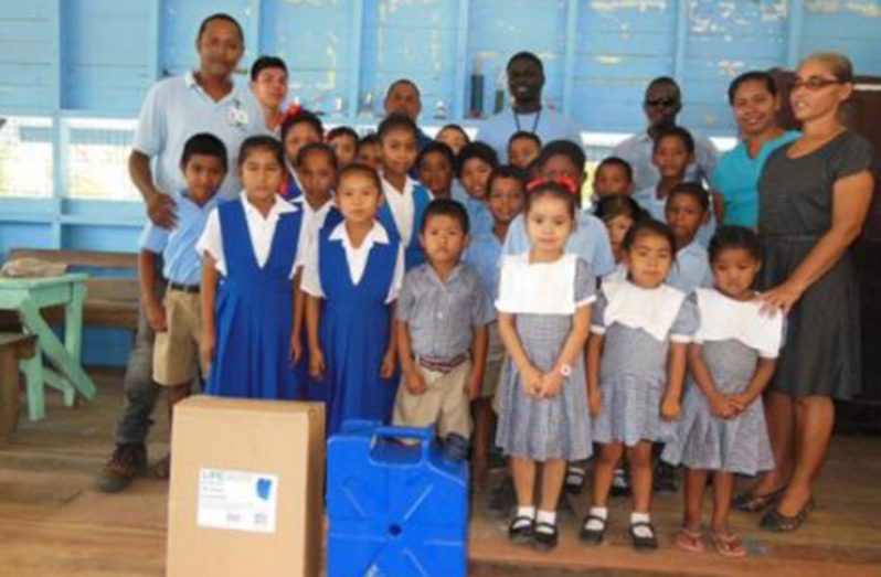 GWI officials pose with teachers and students of Karrau Creek Primary School who received water filters