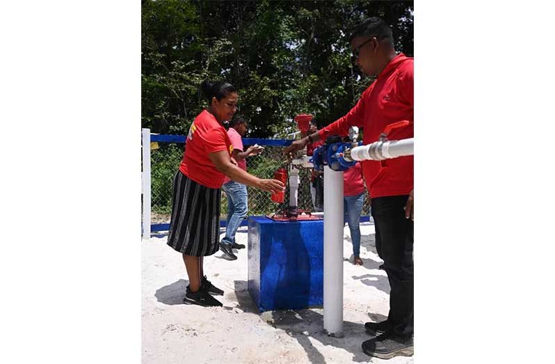 A resident of Bethany samples water from the new water supply system