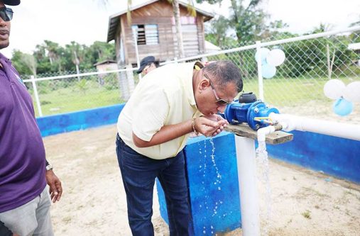 Minister Croal takes a drink from the water-supply system that was commissioned at New Found Out, Region 10, on Saturday