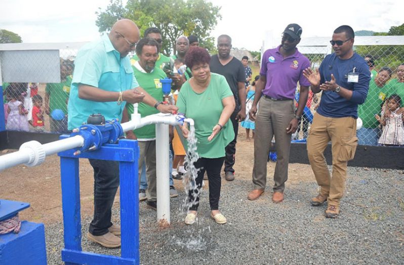 Dr. Van West-Charles (left) and Minister of Social Protection Amna Ally turn on the tap to signal the commissioning of the Moco Moco Water Supply System last month