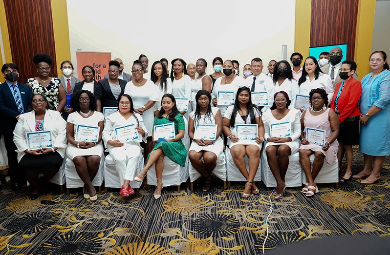 The graduates display their certificates while in the company of officials