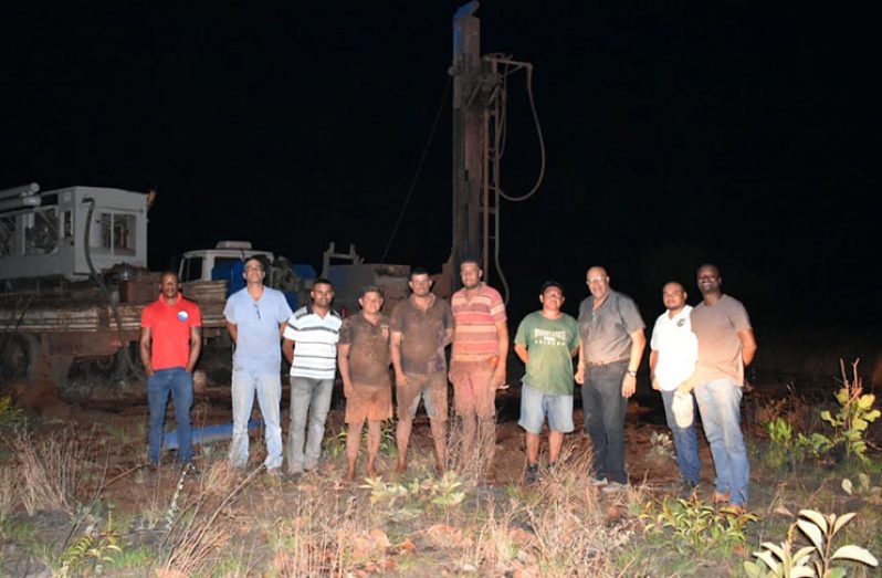 GWI officials including Managing Director, Dr Richard Van-West Charles, Brazilian drillers from Fox Services & Trading and Nappi Village Toshao pose for photo in front of the drilling rig in Nappi, Region 9