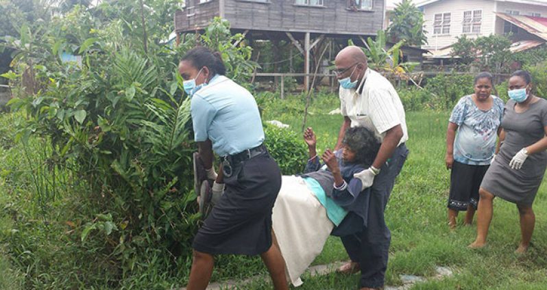 The woman being taken by Suresh Sugrim of the NJASHM and a police officer from her home to the waiting ambulance