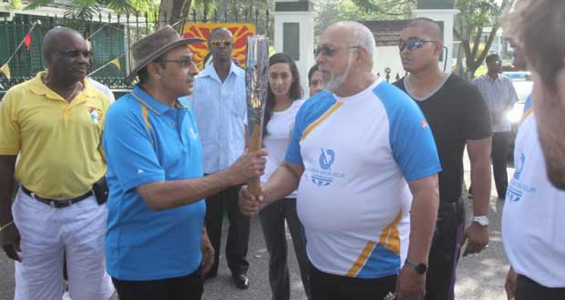 Guyana Olympic Association president Kamal Juman-Yassin (left) hands over the Queen’s Baton to President Donald Ramotar during the Glasgow 2014 Commonwealth Games relay. (Sonell Nelson photos)