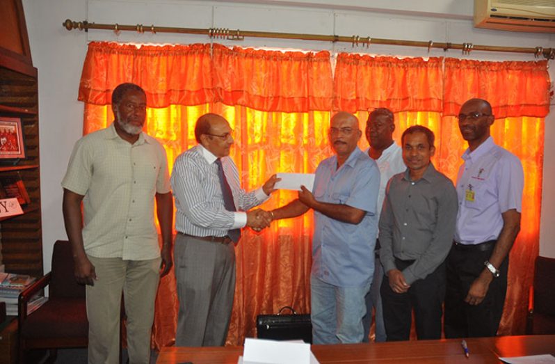 President of the GOA, K. Juman Yassin presents the cheque to the GuyanaNRA captain Mahendra Persaud in the presence of members of both associations.