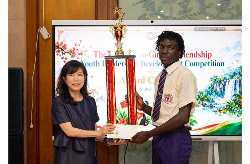 Chinese Ambassador to Guyana Yang Yang presents a trophy to President’s College student Romario Wolfe during the fifth China-Guyana Friendship Youth Leadership Development Competition awards ceremony. (Elton John photo)