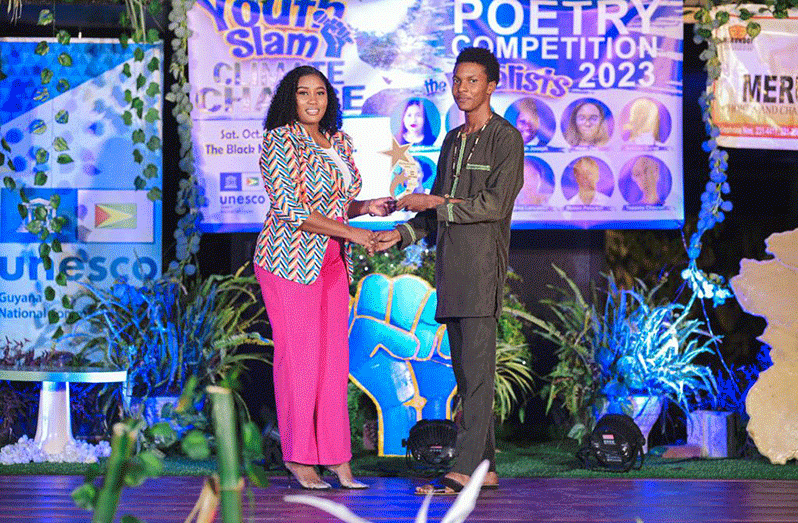 Ezikel Alleyne (right) receives the Dr. Olato Sam trophy for the Most Inspiring Poem from Nikki Sam, wife of the late Dr. Sam. As the time of his death, Dr. Sam was the Secretary-General of Guyana National Commission for UNESCO